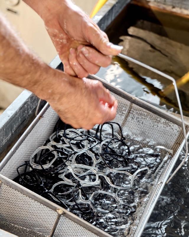 Artisan inspecting CNC milled metal eyewear components in Cadore workshop
